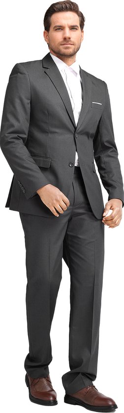Man in donkergrijs slim fit pak met wit overhemd, staand, met hand in broekzak.