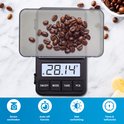 Balance numérique avec des grains de café, affichage 28,14g.