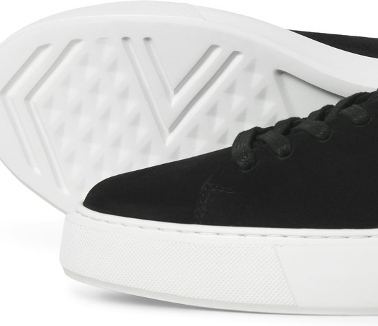 Close-up van de zool en zijkant van een zwarte suède sneaker met witte zool.