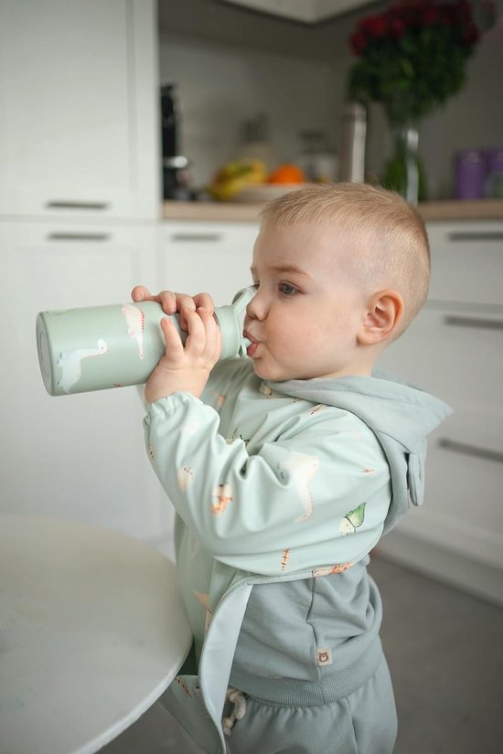 Jongetje drinkt uit een lichtgroene drinkfles met dinosaurusprint.