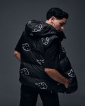 Model in zwarte puffer bodywarmer met witte wolkenprint, van achteren gezien.