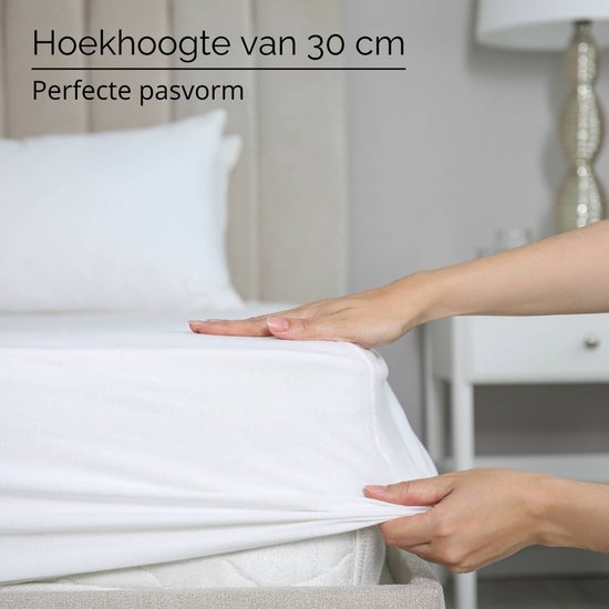 Handen die een wit molton hoeslaken met een hoekhoogte van 30 cm op een matras leggen.