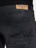 Close-up achterkant van een zwarte spijkerbroek met leren label en sierstiksels op de zakken.