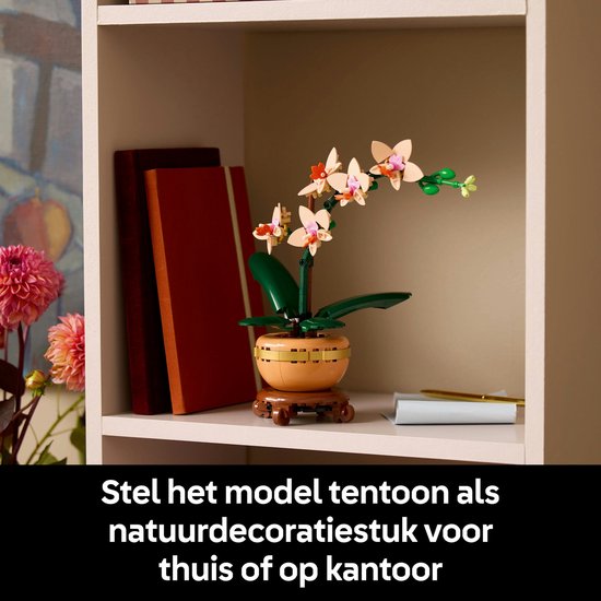 Een LEGO orchidee op een plank naast boeken, als decoratie voor thuis of op kantoor.