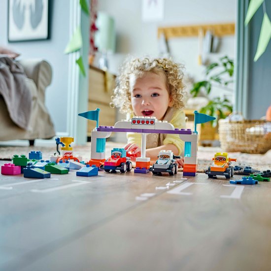 Un enfant joue avec les voitures et pilotes de course équipe F1 LEGO Duplo
