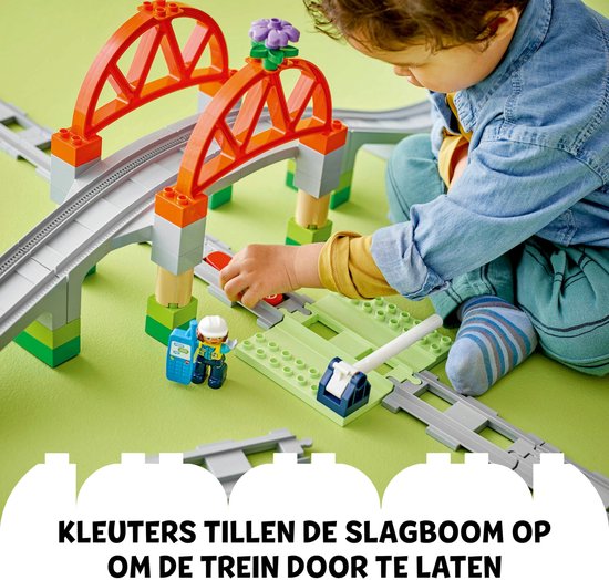 Jongetje met Duplo treinbaan: hij tilt de slagboom op zodat de trein kan passeren.