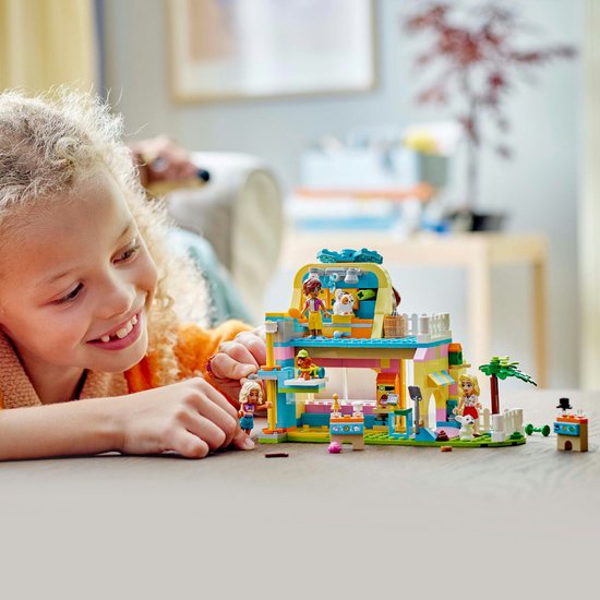 Fille jouant avec un set LEGO Friends de boutique d'accessoires pour animaux, aux couleurs rose, jaune et bleu.