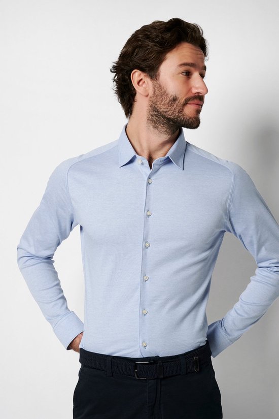 Homme portant une chemise en jersey bleu clair, mains dans les poches