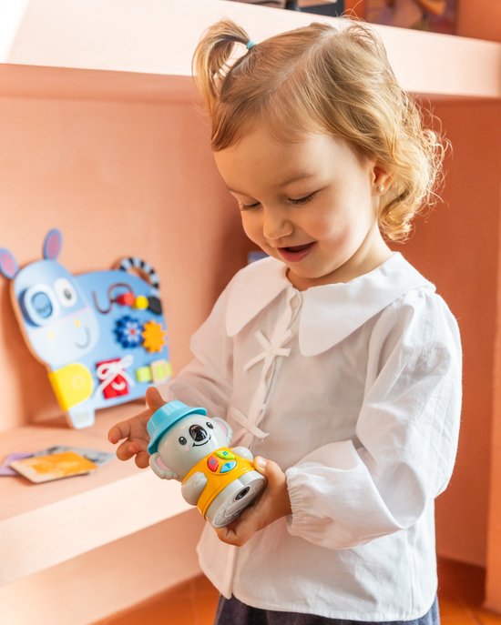 Kind vasthoudend koala speelgoed met blauwe hoed en oranje shirt.