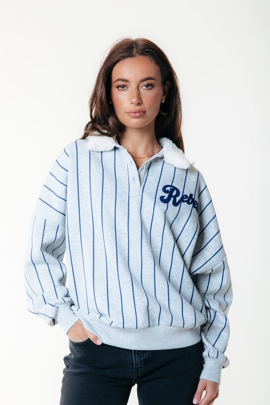 Mannequin portant un sweat gris clair à rayures verticales bleu foncé, col blanc en teddy et le logo 'Rebel' sur la poitrine.