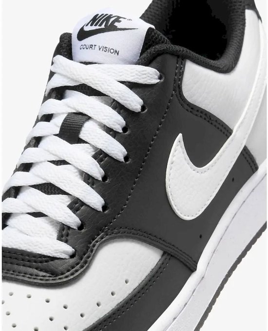 Close-up van de voorkant van een witte en zwarte Nike Court Vision Low sneaker met witte veters en een witte swoosh.