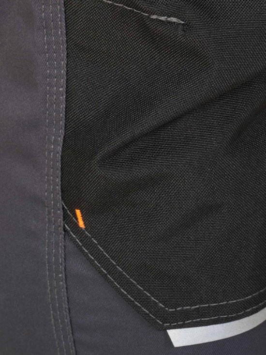 Détail du pantalon de travail gris foncé avec une poche noire et une bande réfléchissante.