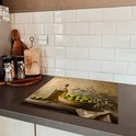 Planche à découper avec peinture d'olives vertes dans un bol, une bouteille d'huile d'olive et des branches d'olivier.