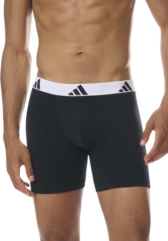 Man met zwarte boxershorts met brede, witte Adidas-band met logo's.