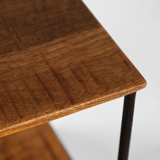 Close-up van een mangohouten plank met een verweerd uiterlijk en een deel van het zwarte metalen frame.