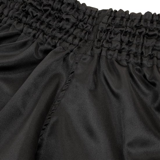 Detailopname van de zwarte satijnen stof en de geplooide elastische tailleband.