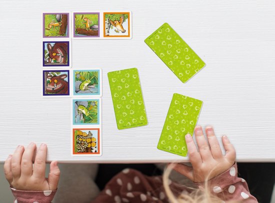 Gruffalo domino kaarten en groene speelkaarten op een witte tafel, gefotografeerd van bovenaf.