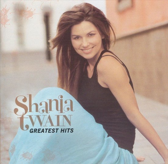Shania Twain met "Greatest Hits" hoes, ze draagt een zwarte tanktop en een lichtblauwe rok.