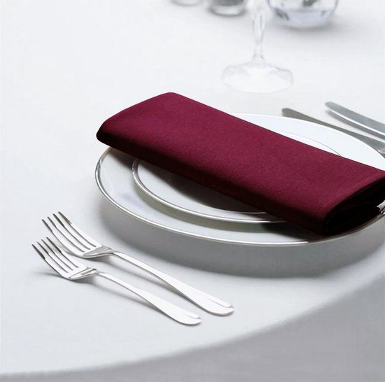 Wit tafelkleed met een stapel witte borden, een bordeauxrood servet en bestek.