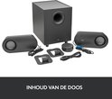 Inhoud van de doos: zwarte subwoofer, twee grijze speakers, volumeknop, stroomkabels en standaards.