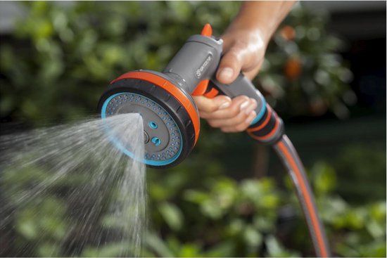 Grijze GARDENA spuit met oranje en blauwe accenten sproeit water.
