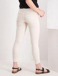 Achterkant model in lichte, skinny jeans met rafels en zwarte sandalen.