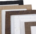 Close-up van een stapel fotolijsten in de kleuren zwart, beige, bruin en wit met een verweerde textuur.