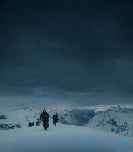 Een groep mensen trekt door een besneeuwd berglandschap onder een dreigende donkere hemel.