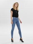 Model in een zwarte top met panterprint en lichtblauwe skinny jeans. Zwarte laarzen.