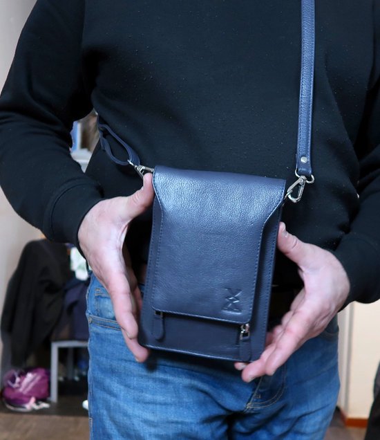 Donkerblauwe leren crossbody tas gedragen door een man.