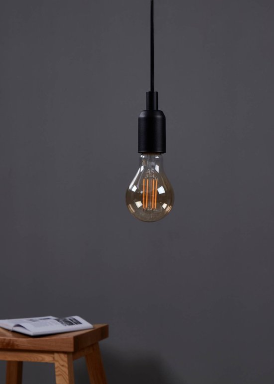 Lampe suspendue noire avec une ampoule ambrée de type poire avec filaments apparents.
