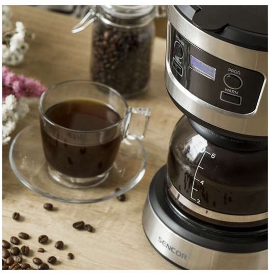 Koffiezetapparaat Sencor met glazen kan vol koffie, naast een mok met koffie en koffiebonen.