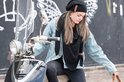 Jonge vrouw met zwarte gebreide muts en sjaal, op een scooter.