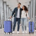 Man en vrouw, beide met een blauwe Voyageux reiskoffer, lopen samen door een moderne gang.