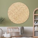 Décoration murale ronde en rotin avec motif tressé, au-dessus d'un berceau en bois dans une chambre d'enfant verte.