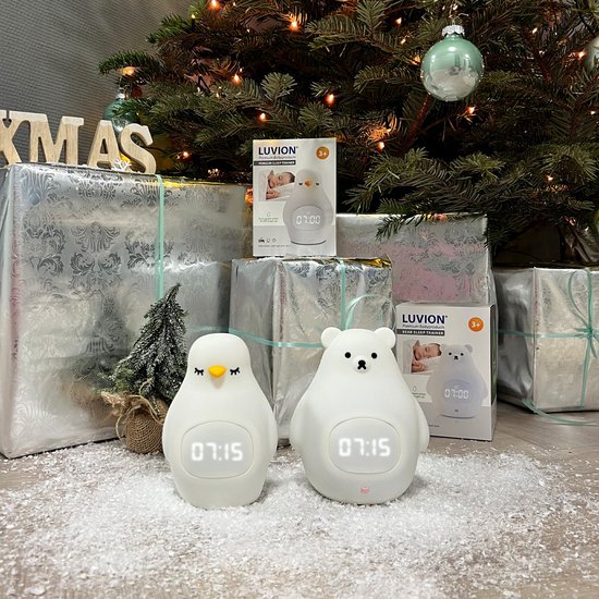 Een witte vogel- en een witte beer-slaaptrainer in de sneeuw naast een kerstboom en cadeaus. Beide tonen digitale tijd.
