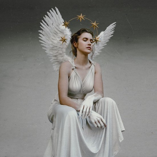 Une femme en robe blanche avec de grandes ailes d'ange blanches et une auréole d'étoiles dorées au-dessus de sa tête.