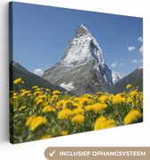 Canvas Schilderij De Matterhorn in Zwitserland boven een paardebloemweide - 80x60 cm - Wanddecoratie