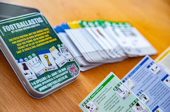 Dichte opname van een blikje 'Footballastic' met opengeklapte kaartspellen, deels op een houten tafel.