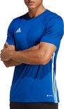Man met gekruiste armen in een kobaltblauw Adidas T-shirt met witte strepen op de zijkanten.