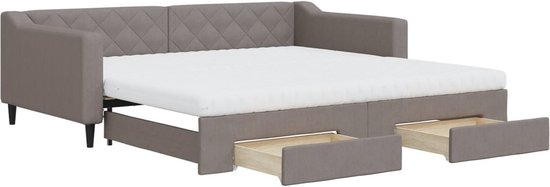 Grijze slaapbank met diamantstiksels, uitgeschoven matras en twee lades.