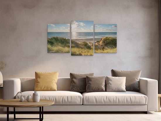 Triptyque d'une plage ensoleillée avec herbes des dunes, mer et ciel, au-dessus d'un canapé.