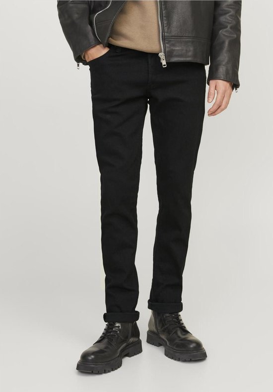 Man in een zwarte skinny jeans, zwarte leren jas en omgerolde broekspijpen.