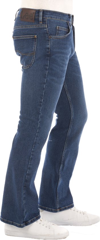 Man in een blauwe bootcut jeans van Lee met een witte sneaker, zijaanzicht.