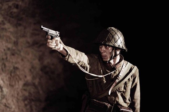 Soldaat met helm en pistool, gericht. Militair uniform met bandelier.