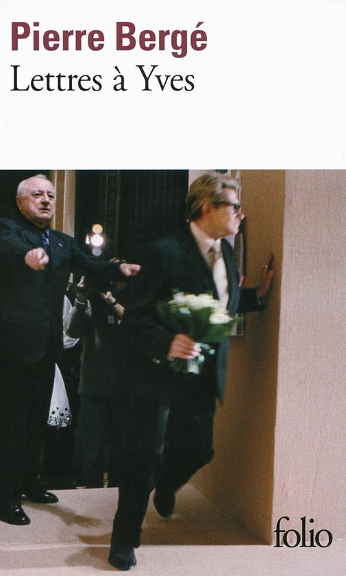 Livre avec texte 'Pierre Bergé Lettres à Yves'. Un homme en costume sombre, portant des lunettes, tient un bouquet de fleurs blanches.