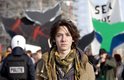 Jonge man met bruin haar, sjaal en jas voor protest met walvisstaarten en 'SEA SHEPHERD' vlag.