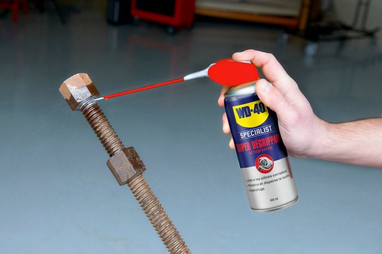 Hand spuit WD-40 Specialist Super Degrippant op een roestige bout.