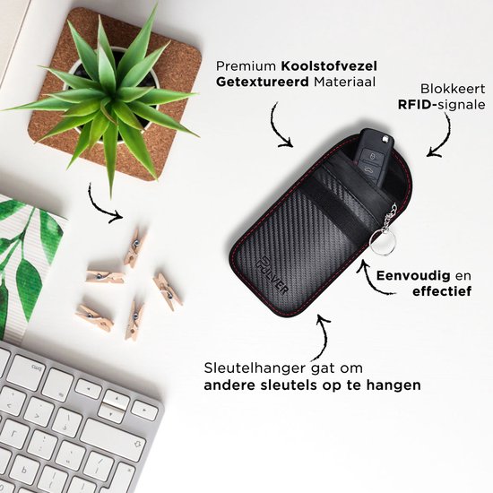 Zwart autosleuteletui met carbonlook, sleutel in etui, naast een toetsenbord en plant.
