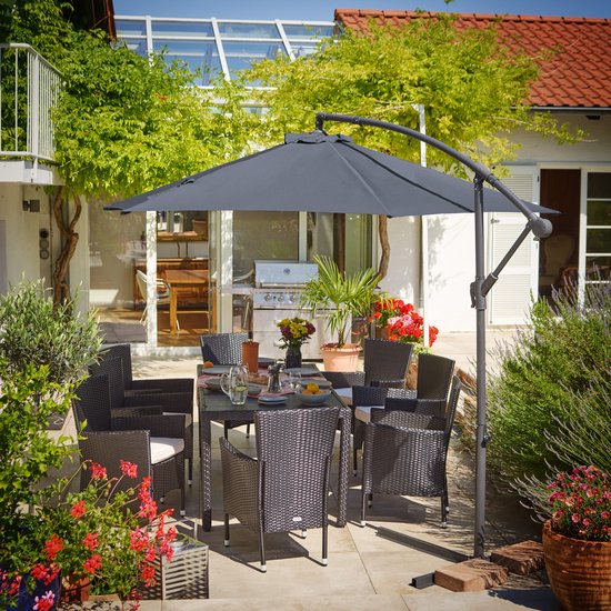 Een gezin geniet van een maaltijd aan tafel onder een donkergrijze zweefparasol op een zonnig terras, met zwembad.